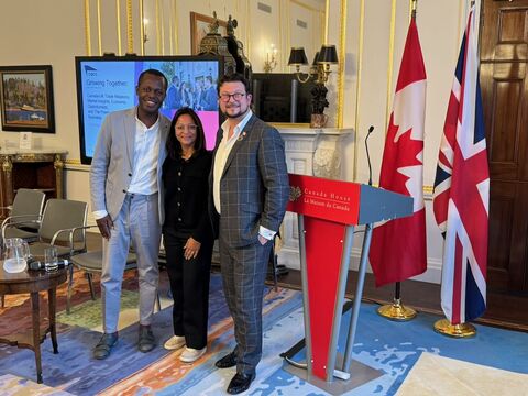 Three people at the Canada House event beside UK and Canadian flags.